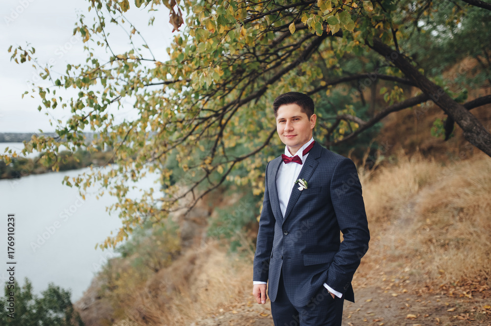 Handsome young man on a background of autumn nature and lake. Portrait of the groom. Handsome young man on a background of autumn nature and lake. Portrait of the groom.