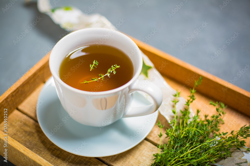 Thyme tea in white cup on a wooden tray, side view. Bokeh. Close up. Copy space