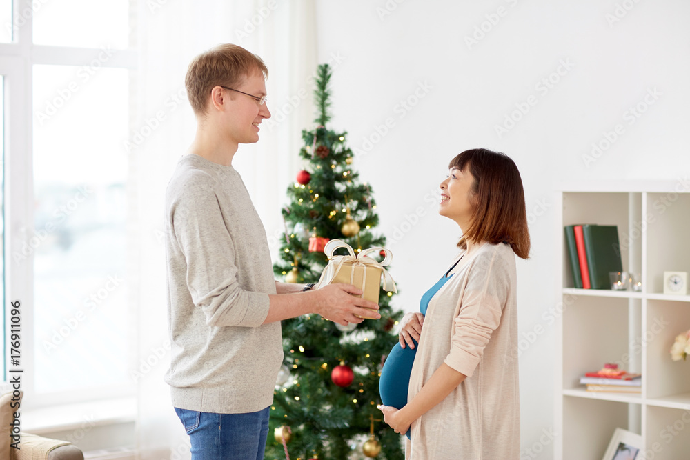 husband giving christmas present to pregnant wife husband giving christmas present to pregnant wife