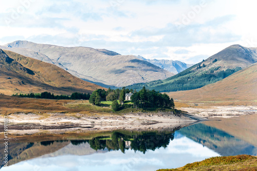 Beautiful view with scottish house in mountains lake and forest