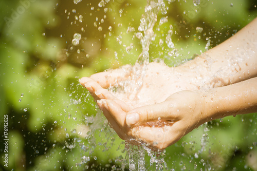 Woman washing hand outdoors. Natural drinking water in the palm. Young hands with water splash, selective focus. Instagram