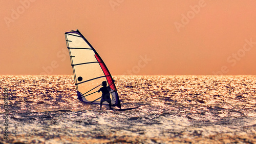 Fotografie Windsurfer silhouette against a sunset background
