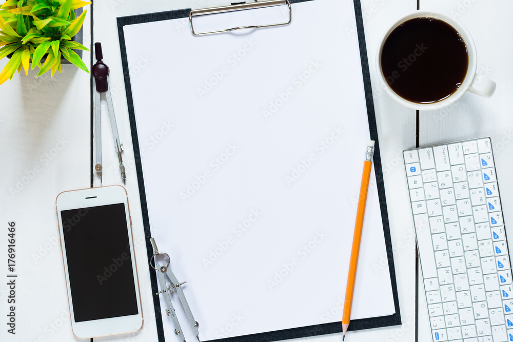 Top view of blank white paper sheet, black stationery items, several drawing tools, coffee cup and smart phone on wooden desktop. Top view of blank white paper sheet, black stationery items, several drawing tools, coffee cup and smart phone on wooden desktop.