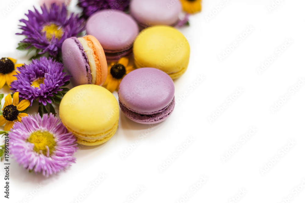 Colorful macarons, flowers and leaves on a white isolated background. Colorful french dessert with fresh flowers. Autumn concept Colorful macarons, flowers and leaves on a white isolated background. Colorful french dessert with fresh flowers. Autumn concept