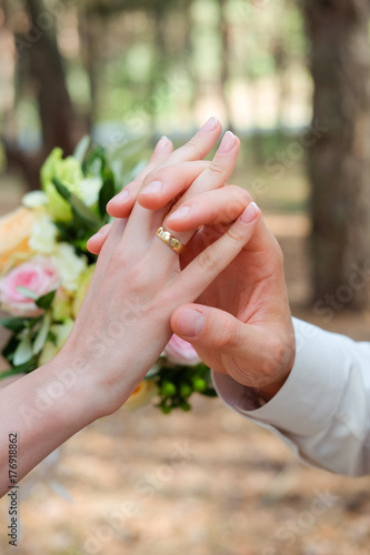Bride and groom holding hands together tenderly wearing wedding rings 
