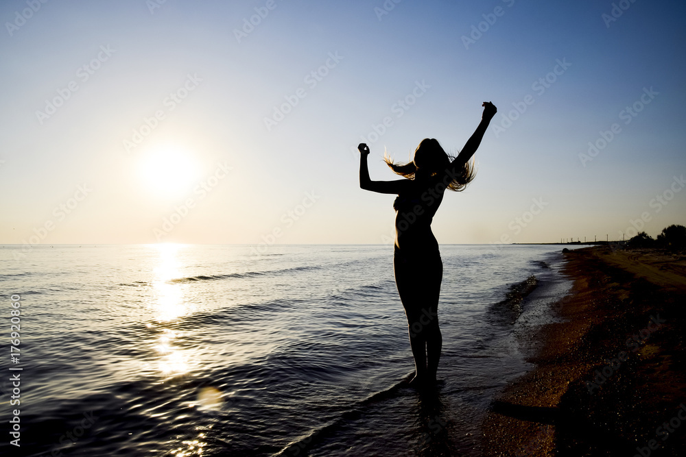 Silhouette of a girl against the sunset by the sea