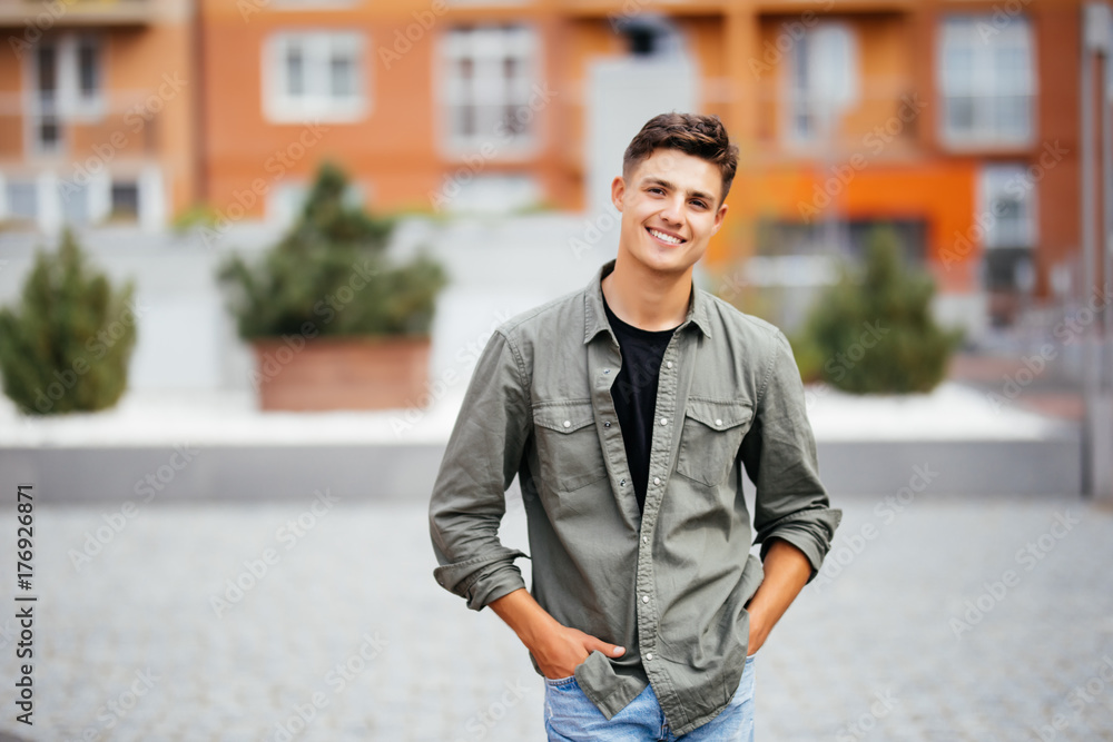 Outdoor portrait of handsome young man walking on the street, looking at camera and smile Outdoor portrait of handsome young man walking on the street, looking at camera and smile