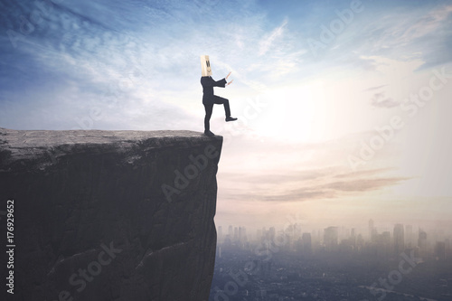 Blindfolded businessman walks on the cliff photo