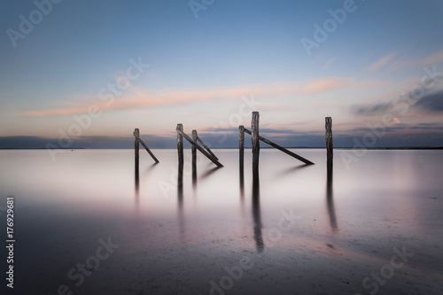 Old jetty poles in a glassy ocean twilight at Flinders, Victoria