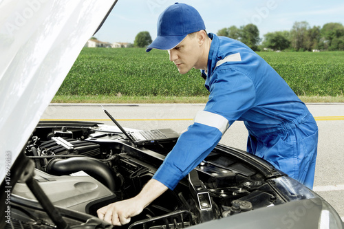 American mechanic checking car on roadside © Creativa Images