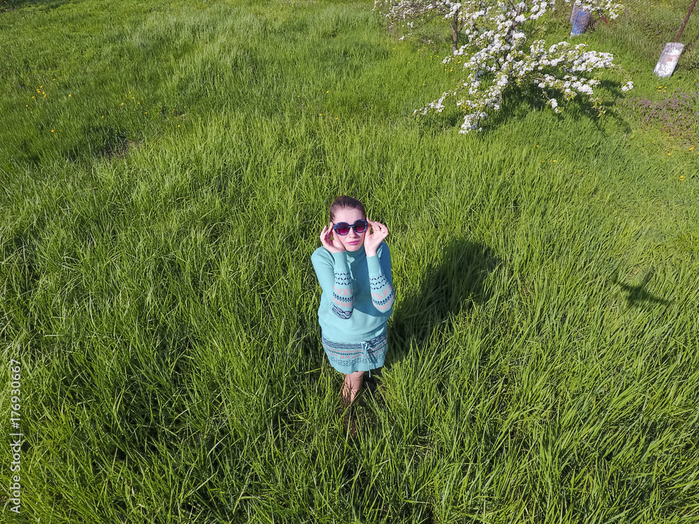 Fototapeta premium Young girl in a light green dress on the lawn with green grass.