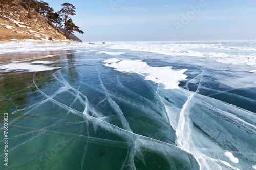 Baikal Lake. Transparent smooth ice with lines of cracks on a sunny winter day