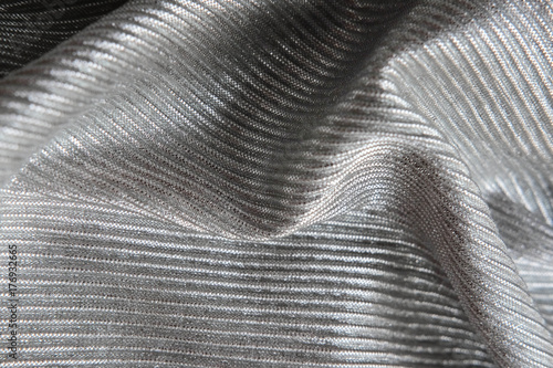 The silver fabric is laid out waves. Black and white canvas material textiles.