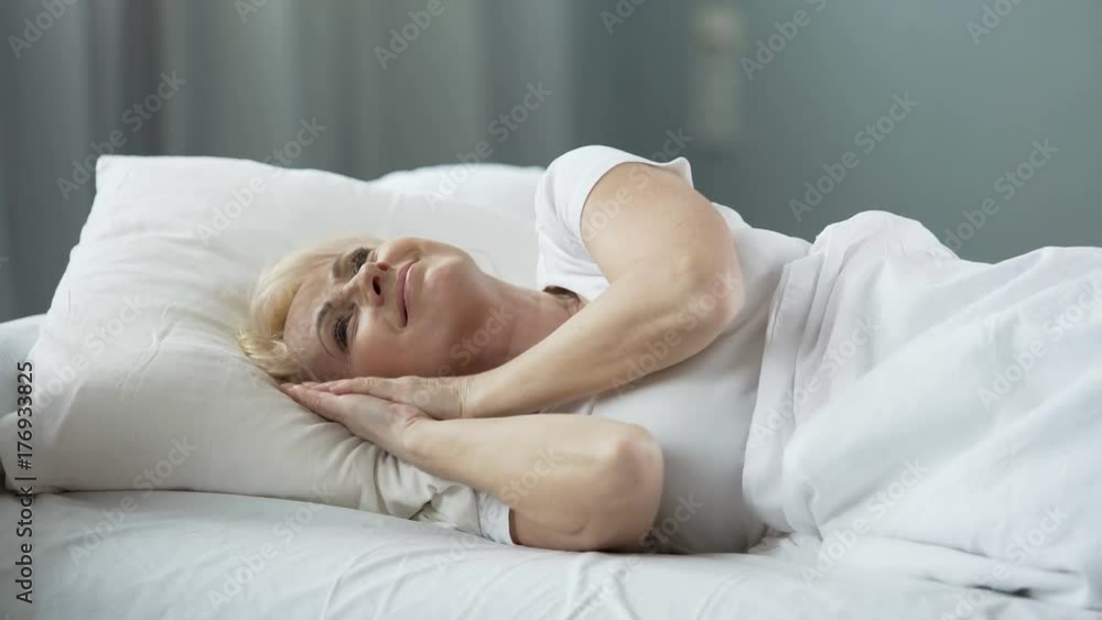 Happy senior female lying in bed and thinking about perfect date, sexual health Happy senior female lying in bed and thinking about perfect date, sexual health