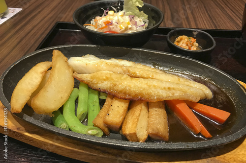 Fish steak in black dish with vegetables