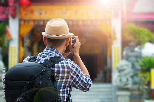Tourist sightseeing old town, travel concept.Street photographer taking a picture of old shrine chinese temple in phuket old town with vintage camera ,rear view and lens flare effect.