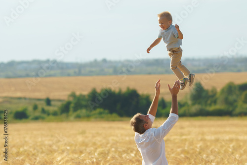 Father playing with son on summer weadow photo