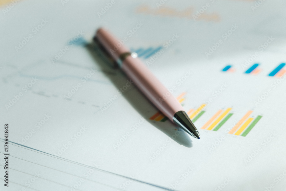 pen placed on information paper has bar chart and other data are background. this image for business, education, info, meeting concept pen placed on information paper has bar chart and other data are background. this image for business, education, info, meeting concept