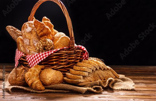 Bakery Assortment on wooden table on dark background. Still Life of variety of bread with natural morning light..