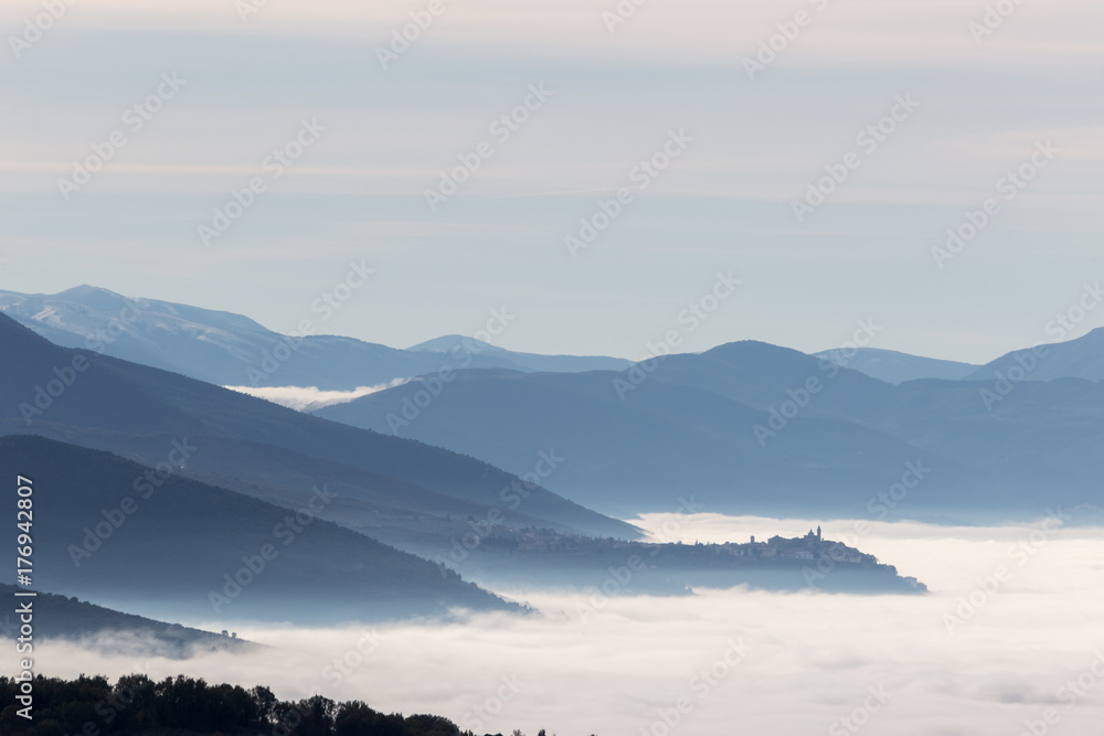 Valley in Umbria (Italy) filled by fog, with Trevi town above the mist