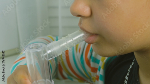 Girl breathing through a steam nebulizer. Treatment bronchopulmonary diseases. Teenager girl with inhaler holds in hands mask vapor. Patients asthma inhalation treatment of respiratory diseases. photo