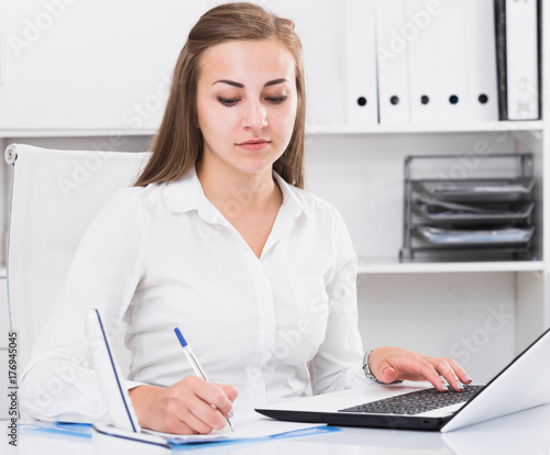 Adult female is working with documents and laptop
