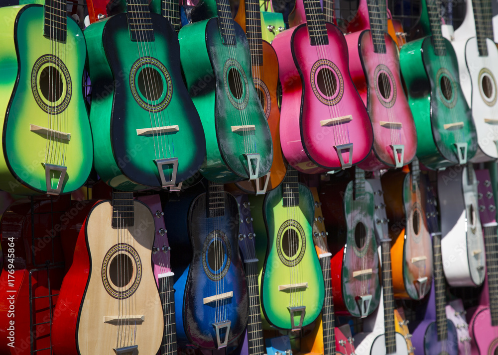 Naklejka premium Sunlit, Angular, Isolated View of Colorful Small Children's Toy Guitars Hanging Up