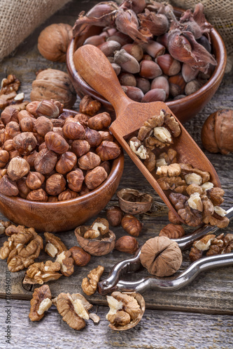 Hazelnuts and walnuts on a spoon and in a linen sack on an old wooden table