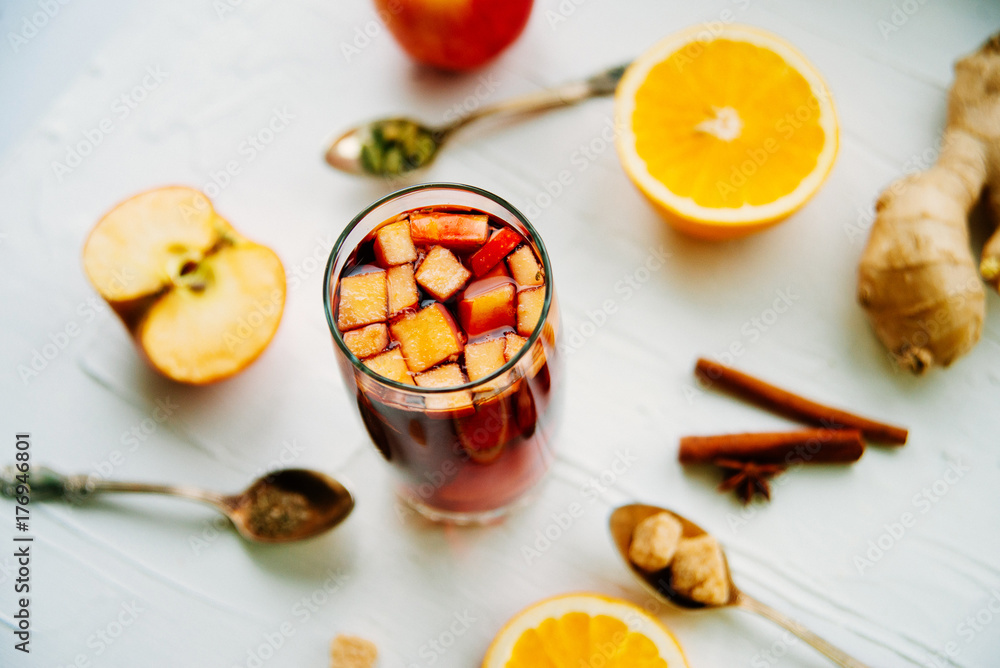 Hot mulled wine or grog cooking for new year celebration with oranges and spices ingredients on light background flat lay Hot mulled wine or grog cooking for new year celebration with oranges and spices ingredients on light background flat lay