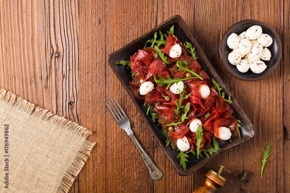 Beef carpaccio served with balls of mozzarella cheese, arugula and capers. Beef carpaccio served with balls of mozzarella cheese, arugula and capers.