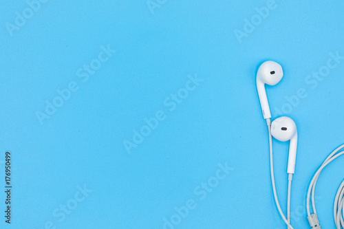 Top view of White Earphones on Blue background. Copy space. Music is my life concept