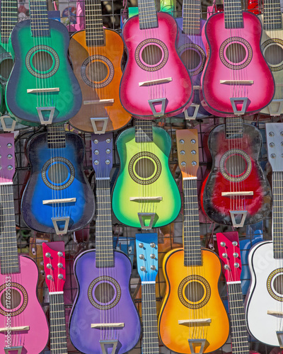Styilized, Isolated Frontal View of Colorful Small Children's Guitars Hanging Up - Horizontal Format