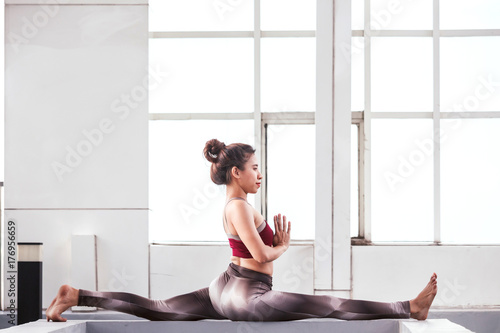 Woman practicing yoga in front of a large window