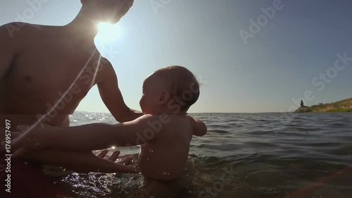 Happy father and baby having fun in the sea, exercising in water photo