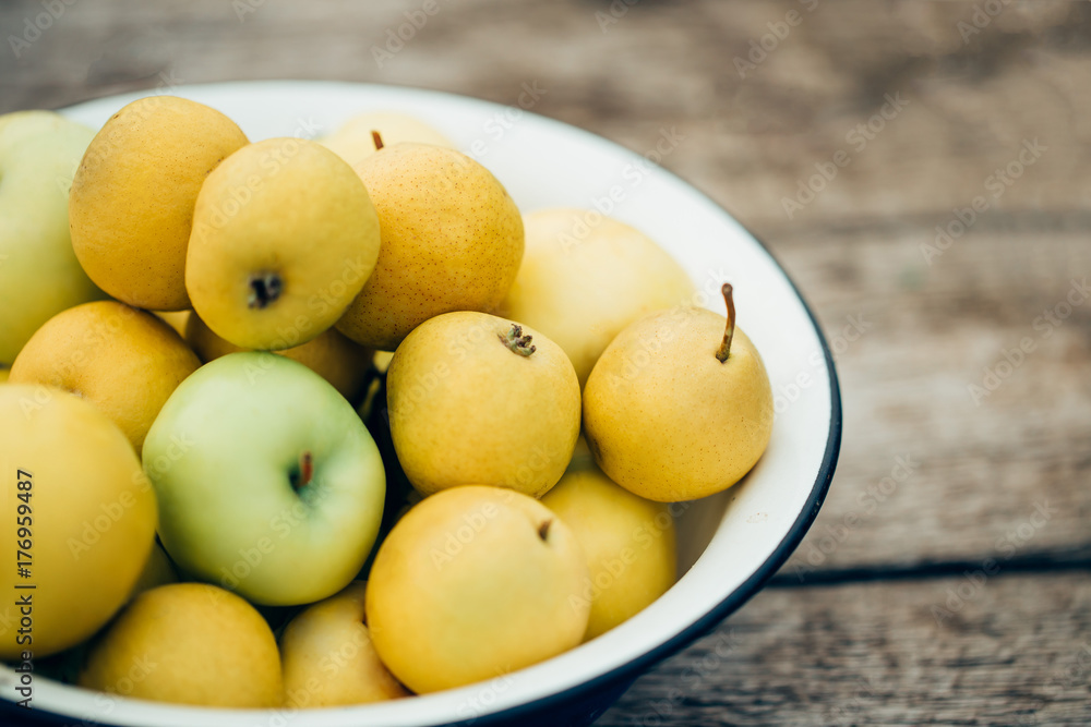 Fresh ripe yellow pears and apples in white bowl on natural wooden background. Selective focus Fresh ripe yellow pears and apples in white bowl on natural wooden background. Selective focus