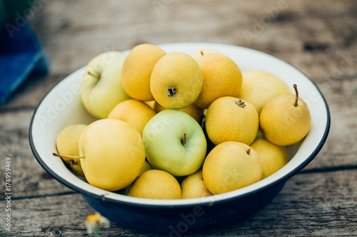 Fresh ripe pears and apples in bowl on natural background. Selective focus