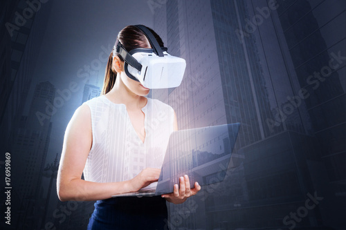 Elegant businesswoman in VR headset working on laptop