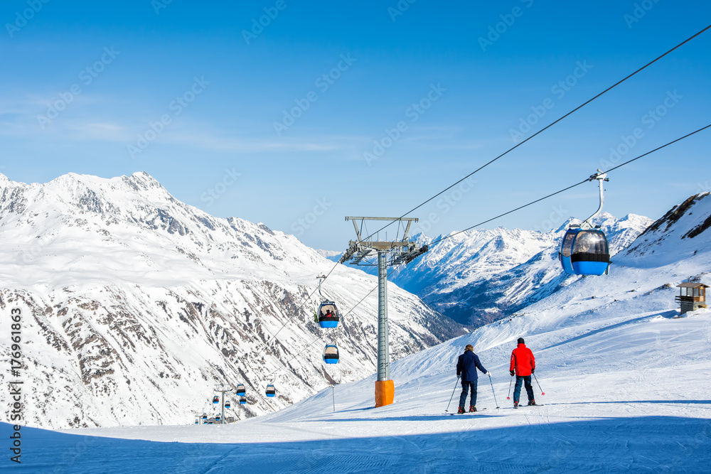 Skiers on the background of high snow-capped Alps in sun day, Austria