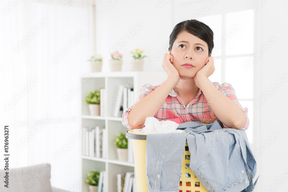woman leaning on laundry basket feeling bored woman leaning on laundry basket feeling bored