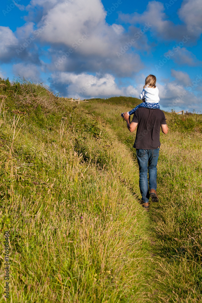 Father and daughter. Dad giving female offspring a shoulder ride. Daddy carrying little girl. Parenting family concept.