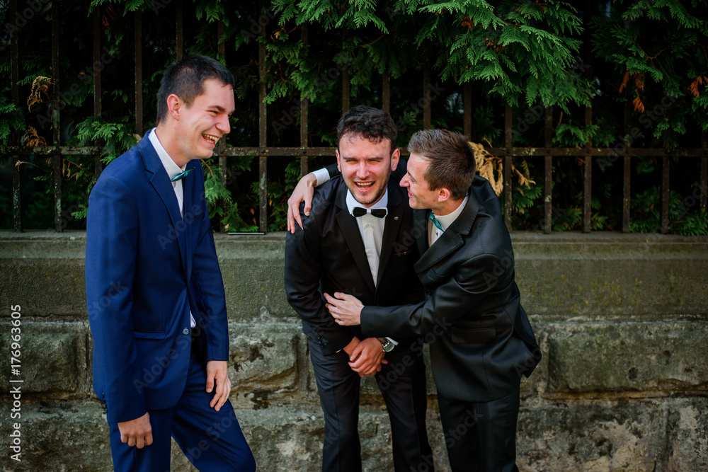 Laughing groom and groomsmen pose outside Laughing groom and groomsmen pose outside