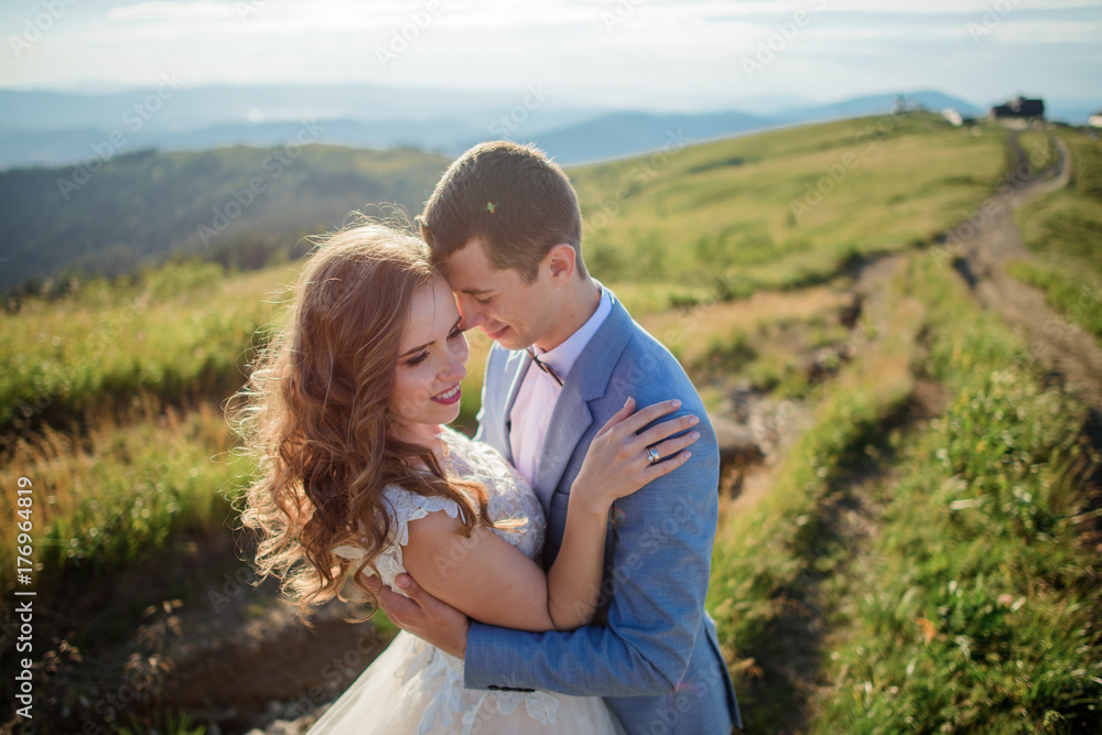 Groom holds bride tender standing before beautiful landscape