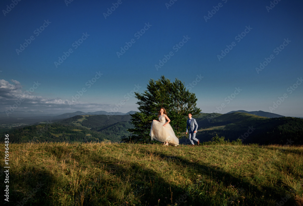 Fototapeta premium Bride runs from groom on the hill