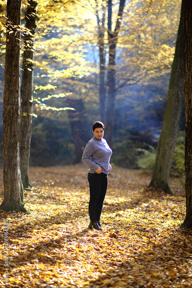 Nice mature woman stands on a background of yellow autumn. Mature woman of the autumn forest. Nice mature woman stands on a background of yellow autumn. Mature woman of the autumn forest.