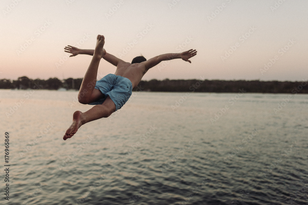 Young boy jumps off wharf into water Young boy jumps off wharf into water