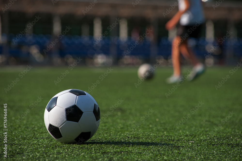 Traditional soccer ball on green grass playground.