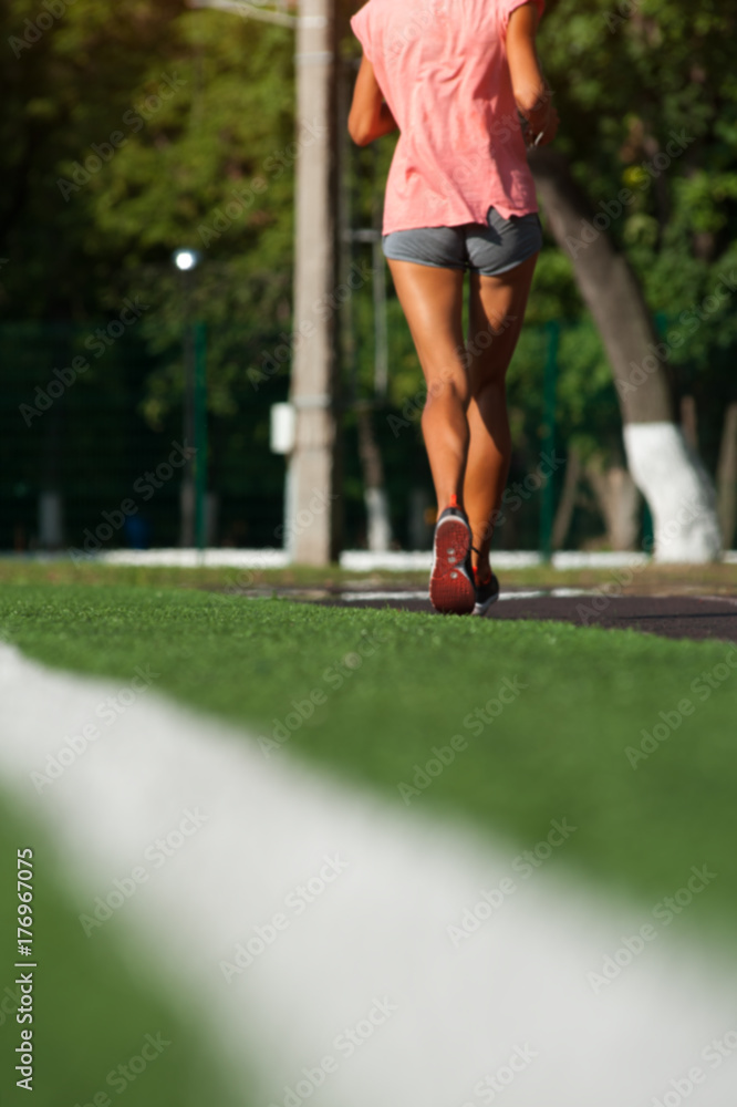 Young woman running on green grass playground