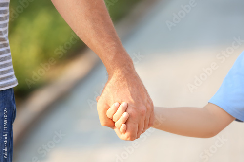 Boy holding grandfather's hand outdoors