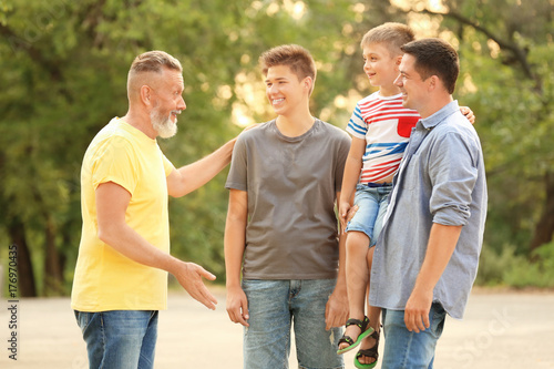 Cute boy with brother, daddy and grandfather in park © Africa Studio