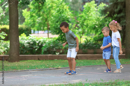 Fototapeta Naklejka Na Ścianę i Meble -  Little children playing hopscotch, outdoors